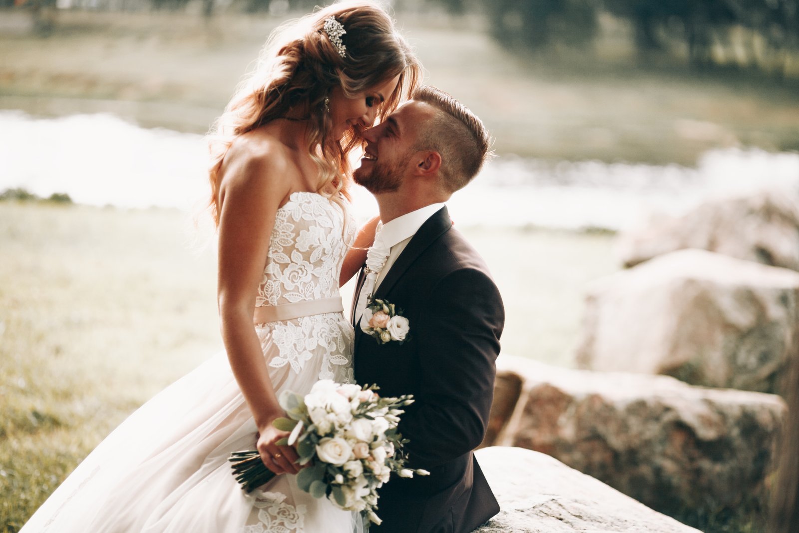 Bride and groom sitting together beside a bright lakeside