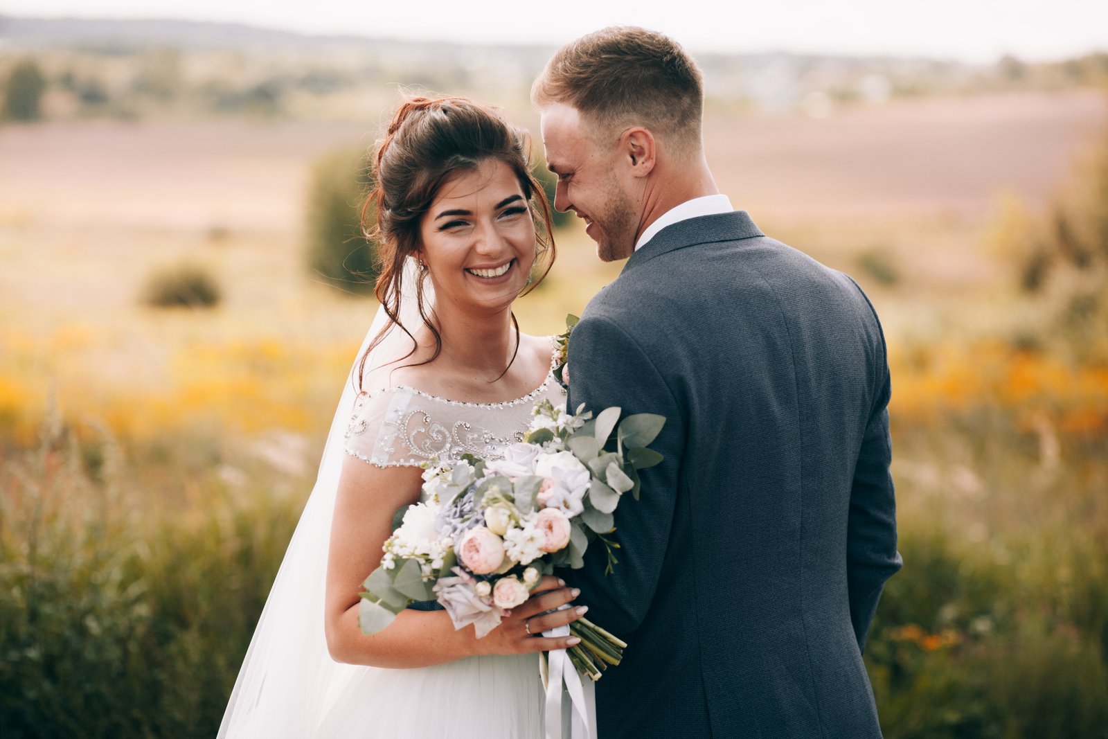 Smiling bride and groom in a sunlit field